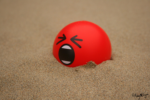 An angry red ball half buried in the sand